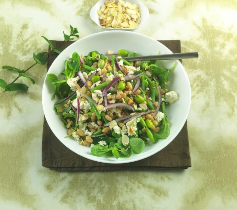 three bean salad with feta cheese in a bowl with toasted sliced almonds on top