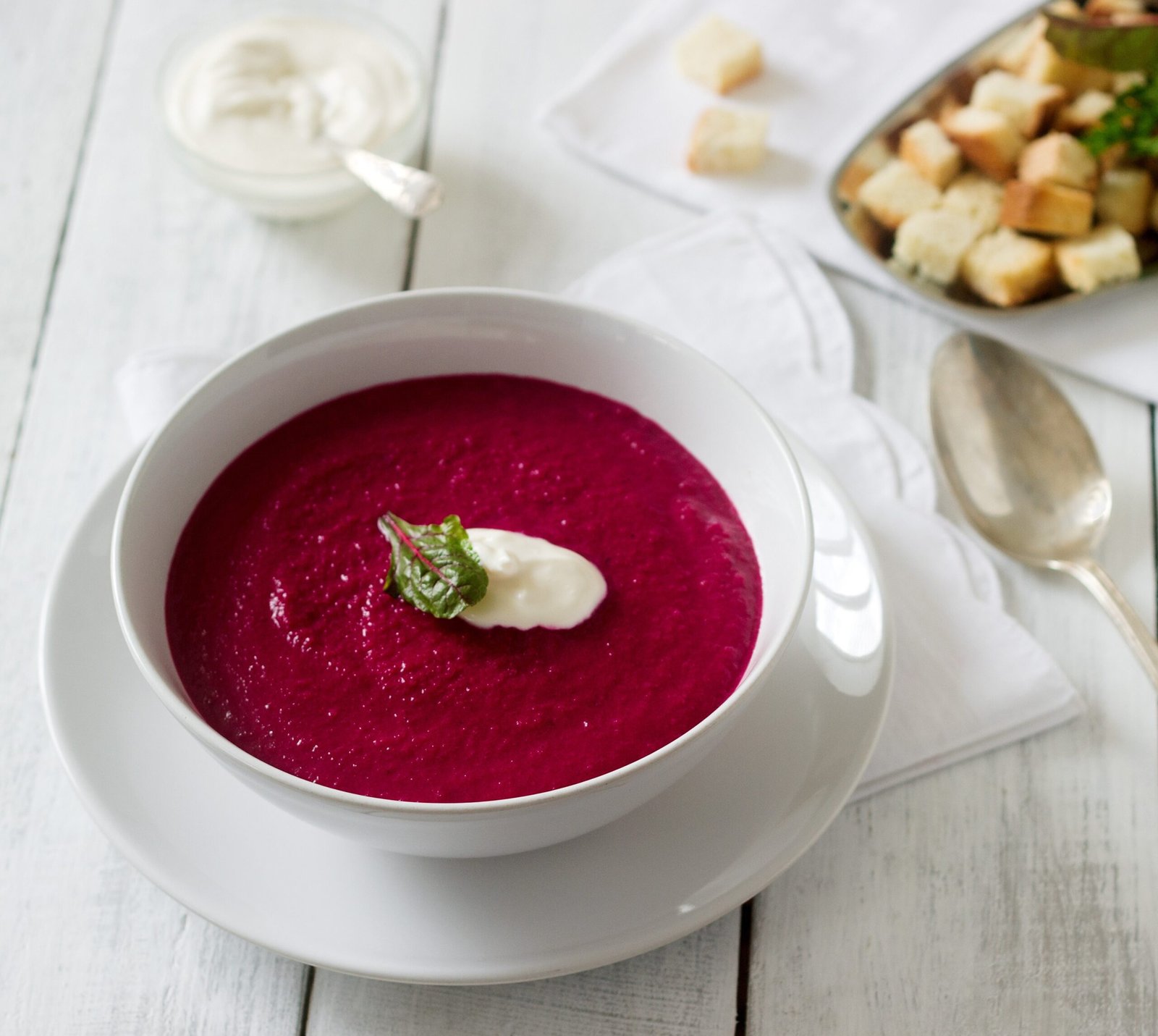 Vibrant crimson beetroot soup garnished with fresh herbs in white bowl, rich in natural nitrates for improved blood flow and sustained energy