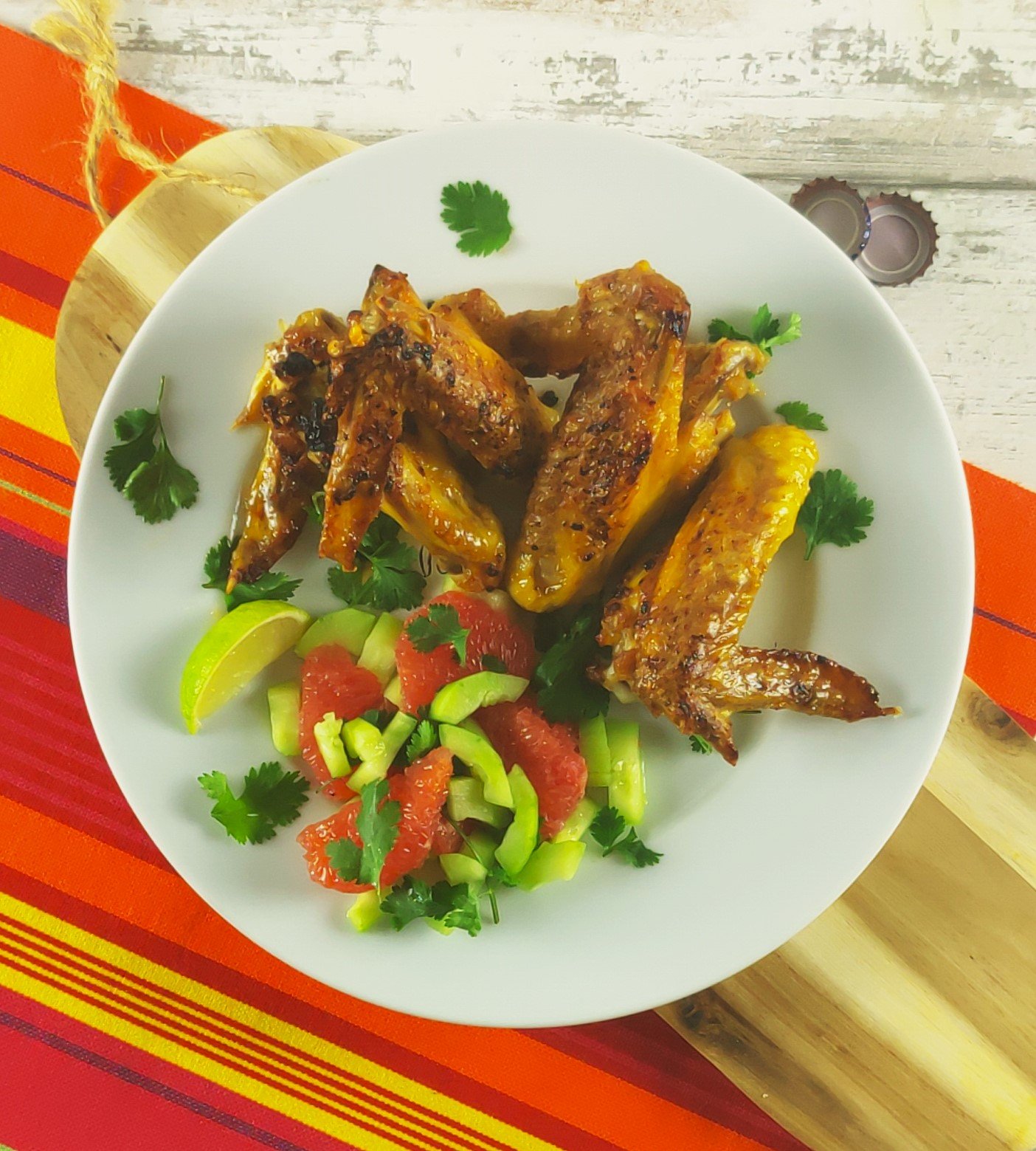 ginger marinated chicken wings tieh grapefruit and cucumber salad on a white plate