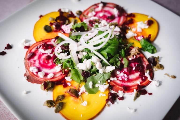 vegetarian beetroot carpaccio with capers, fennel and walnut on a white plate