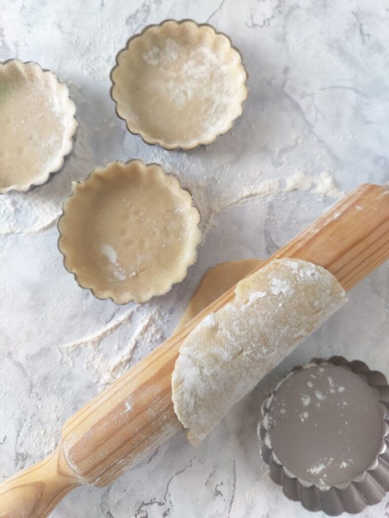 pastry dough rolled out with a rolling pin and tart tins