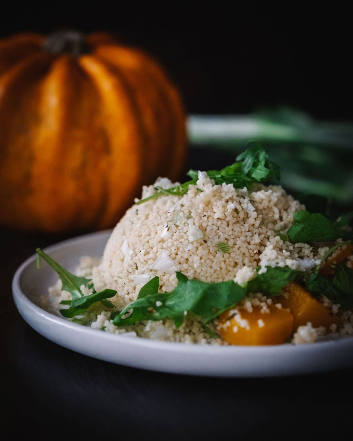 Pumpkin cous Cous Salad with arugula, spring onion and chickpeas on a white plate