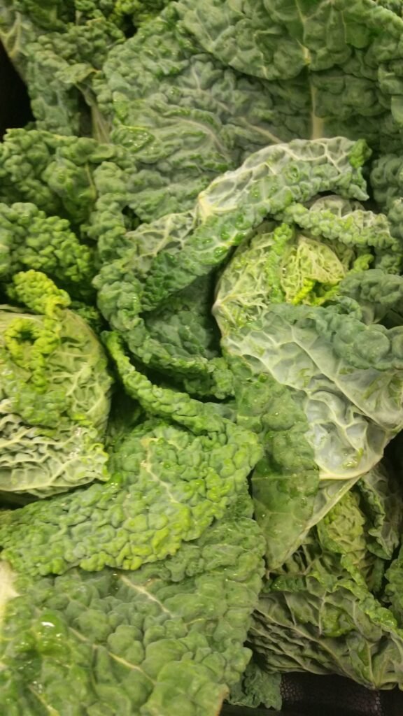 A close-up, high-quality photograph of fresh, green curly cabbage, a nutrient-dense vegetable known for supporting heart health and vascular function in a Mediterranean diet.