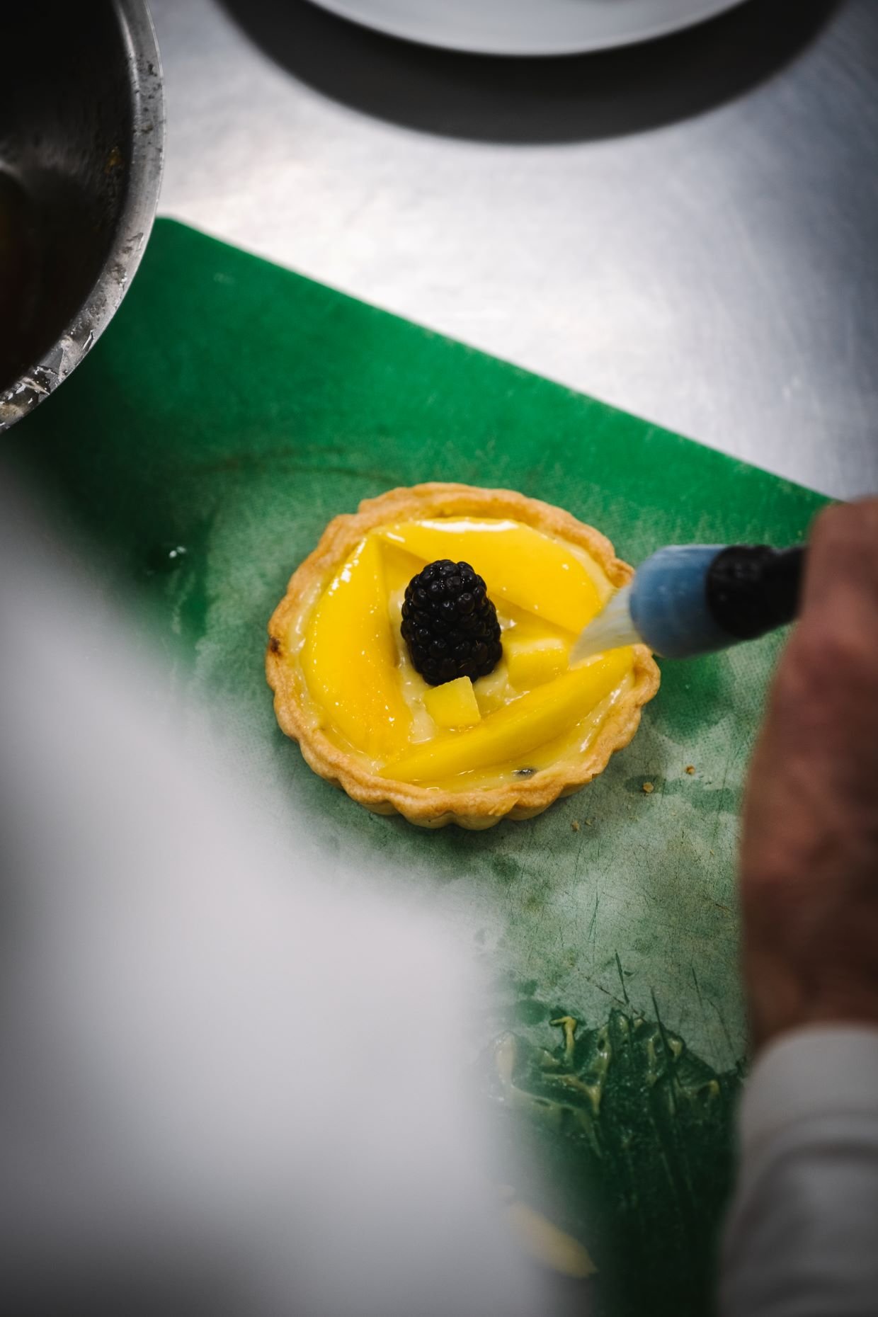 CHEF PUTTING GLAZE ON A MANGO TART