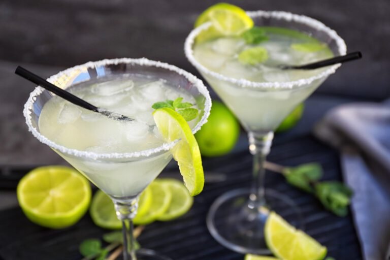 Margarita cocktail in a margaritaglass with salted edges and lime wedges