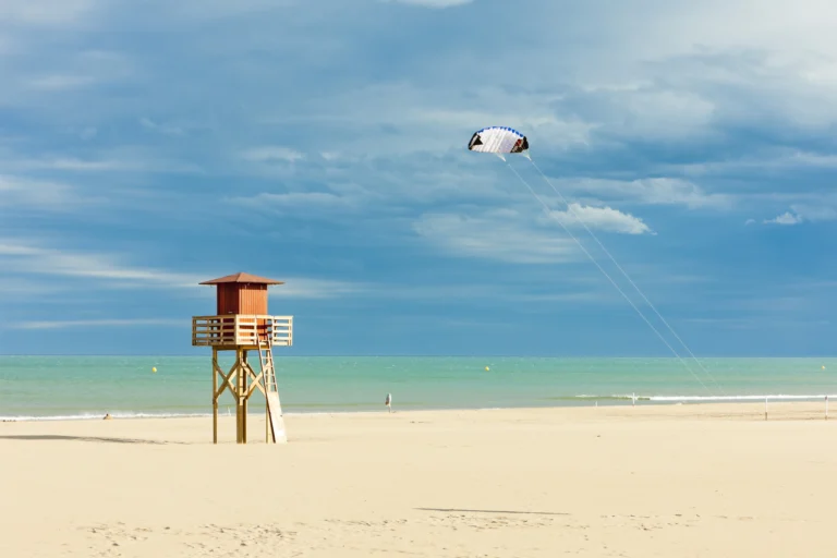 soaking up the sun on a mediterranean beach at Narbonne beach with lifesaver tower and windsurfer