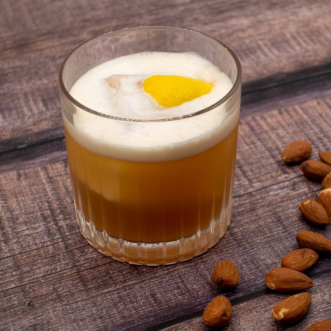Amaretto Gin Sour in a rocks glass with lemon garnish on rustic wooden table