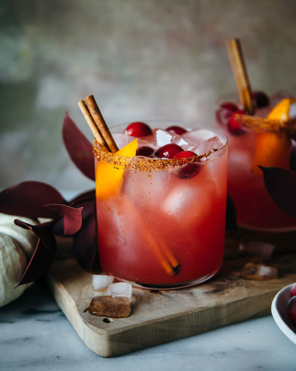 spiced Craanberry margarita with a spiced rim and orange garnish on a wooden board